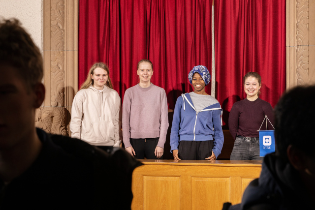 Fire jenter på 15 - 18 år som står på rekke og rad bak et kateter. 