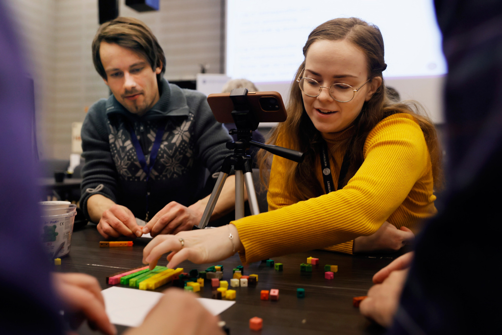 Mann og kvinne som jobber med plastikkbrikker mens de filmer med en mobiltelefon. 