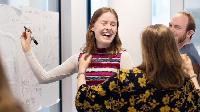 Lærere som ler og skriver på en vertikal tavle