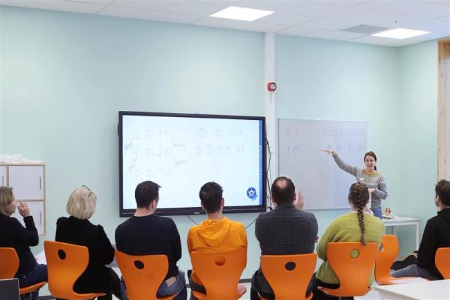 Lærere som sitter foran en smartboardtavle, med ryggen til