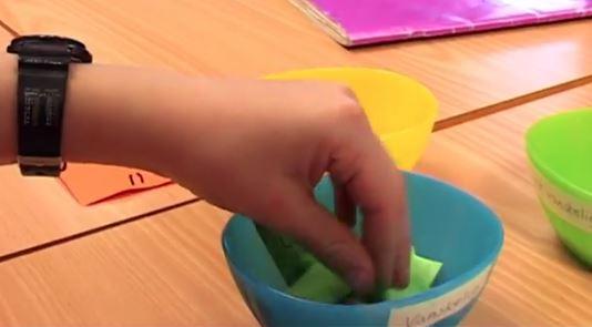 Bilde av en hånd som tar en lapp opp av en bolle