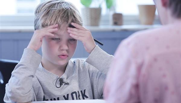 Gutt som tenker mens han jobber med matematikk foran læreren 